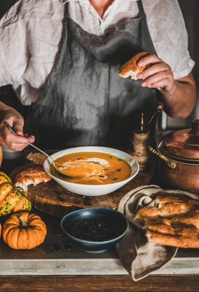 Mujer en delantal gris mezclando crema con sopa de crema de calabaza — Foto de Stock