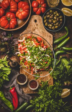 Flat-lay of Turkish Chopard Salad made of fresh seasonal vegetables and herbs with olives and spices on wooden board, top view. Middle eastern, Mediterranean typical cuisine, vegan healthy dish
