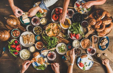 Geleneksel Türk kahvaltı masası ve çeşitli yiyecekler alan insanlar