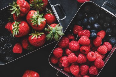 Sağlıklı yaz vejetaryen yemeği. Mevsimlik taze çilekler, ahududular, yabanmersinleri, böğürtlenler koyu arka planda böğürtlenler, üst manzara, yakın çekim. Vejetaryen, vejetaryen, kilo kaybı.
