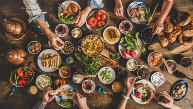 Türk kahvaltısı. Hamur işi, sebze, yeşillik, peynir, sahanda yumurta, doğu sofra takımından reçel, bakır demlikte çay ve kırsal ahşap arka planda lale bardakları, üst manzara.