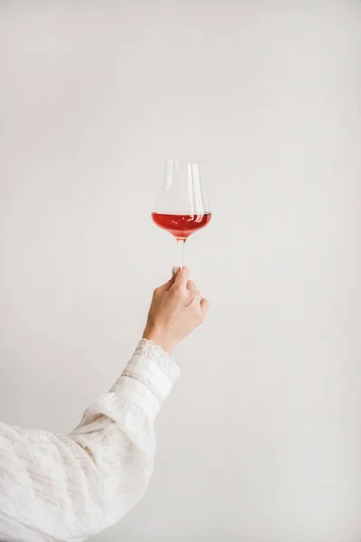 白い壁の背景にローズワインの女性の手を保持ガラス ワインショップ ワインの試飲 ワインリストのコンセプト — ストック写真