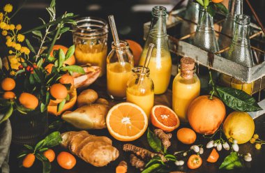 İçkiyi savunmak için vitamin sağlığını arttıran bağışıklık sistemi. Şişelerde zerdeçal, zencefil ve turunçgil suyu iğneleri ve beton mutfak tezgahının üzerinde taze malzemeler, yakın plan. Saf vegan bağışıklık sistemi güçlendirici