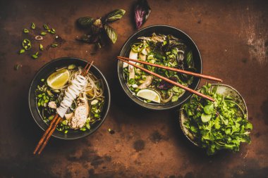 Asya mutfağı yemeği. Vietnam usulü pirinç şehriyeli şehriyeli tavuk çorbası kişniş, soya lahanası, taze yeşillikler, yemek çubuklarıyla kaplı limon, üst manzara. Sağlıklı yemek.