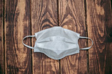 Tahta bir surfac üzerinde beyaz tıbbi maske var.