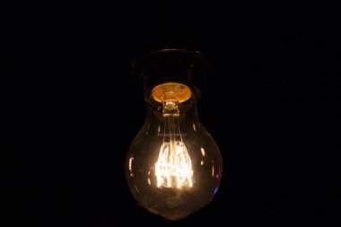 Edison lambası, siyah arka planda hafifçe sallanıyor.
