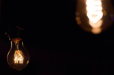 Edison lambası, siyah arka planda hafifçe sallanıyor.