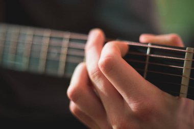 Genç adam akustik gitarla çalıyor.