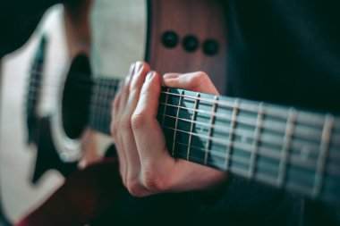 Genç adam akustik gitarla çalıyor.