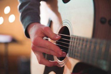 Genç adam akustik gitarla çalıyor.