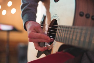 Genç adam akustik gitarla çalıyor.