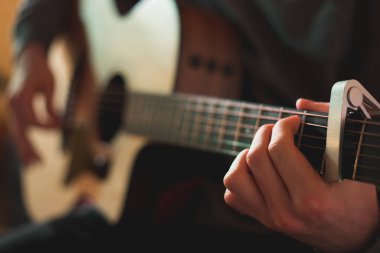 Genç adam akustik gitarla çalıyor.