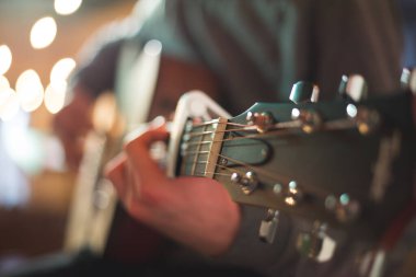 Genç adam akustik gitarla çalıyor.