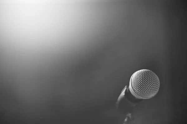 The microphone for the stage stands on a stand on a black background. Black and whire photography.