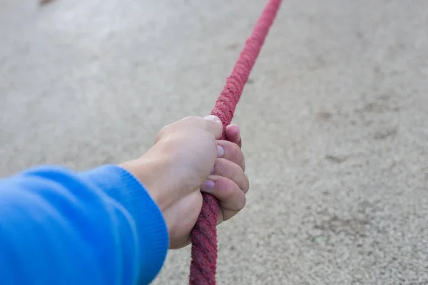 Man\'s hand holds a red rope