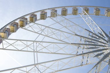 Mavi gökyüzünün arka planında beyaz taksileri olan güzel dönme dolap.