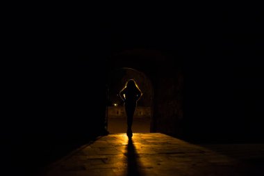 Bir ışık kaynağının önünde duran bir kızın silueti.