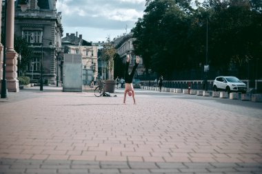 Şehir merkezinde çıplak gövde amuda kalkmış kel yaşlı bir adam.