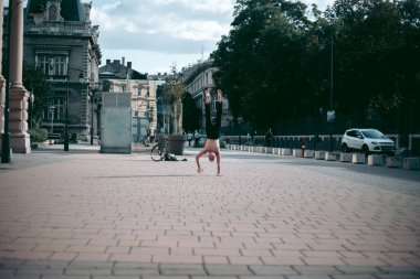 Şehir merkezinde çıplak gövde amuda kalkmış kel yaşlı bir adam.