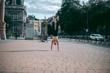 Şehir merkezinde çıplak gövde amuda kalkmış kel yaşlı bir adam.