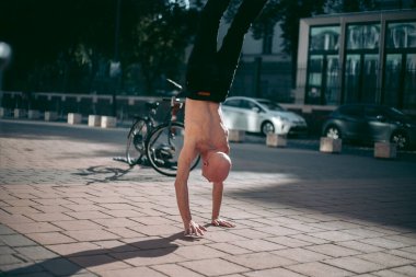 Şehir merkezinde çıplak gövde amuda kalkmış kel yaşlı bir adam.