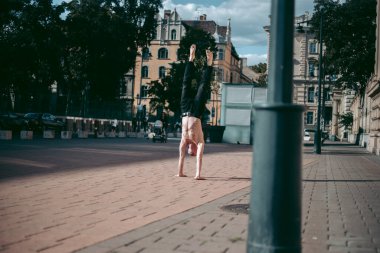 Şehir merkezinde çıplak gövde amuda kalkmış kel yaşlı bir adam.