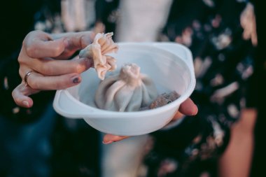 Kız plastik tabakla khinkali yiyor.