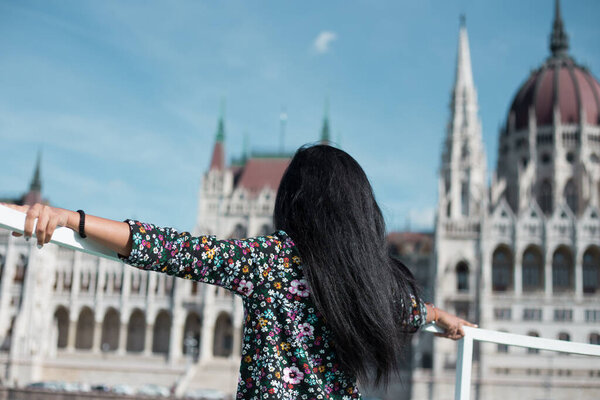 Beautiful young girl looks at the parliament building in Budapest