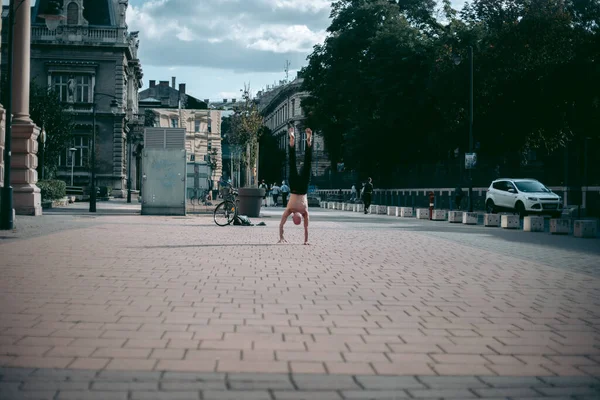 Şehir merkezinde çıplak gövde amuda kalkmış kel yaşlı bir adam.