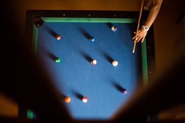 Adam mavi bir masada bilardo oynuyor.