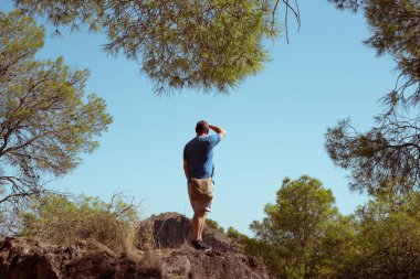 Bir adam uçurumun kenarından şehre bakıyor.