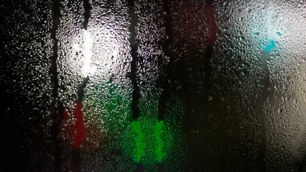 Wet foggy window on a background of lights