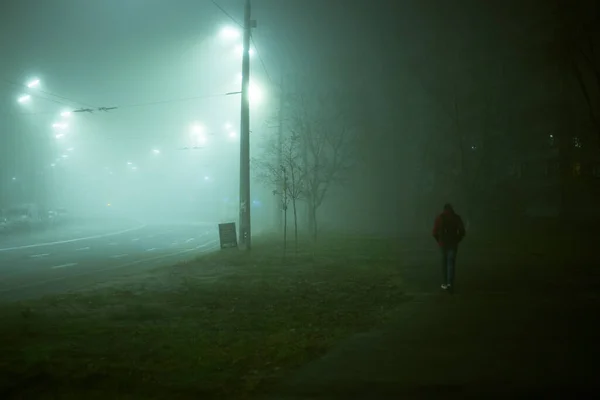 Lonely man at night in the fog in the city