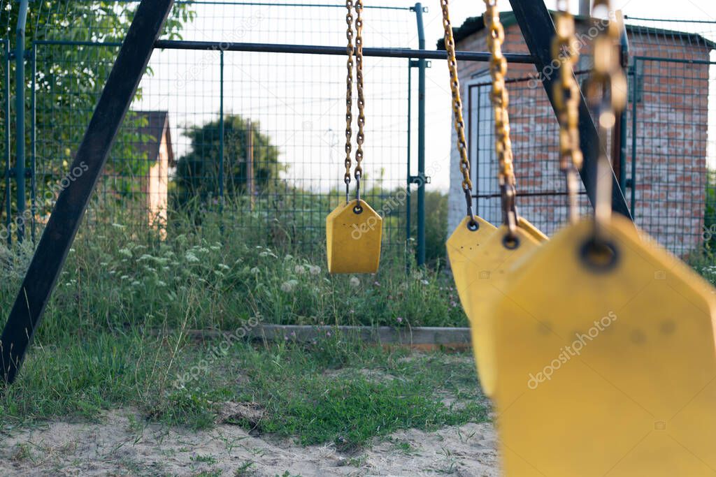 Yellow rubber swing on chains in the backyard