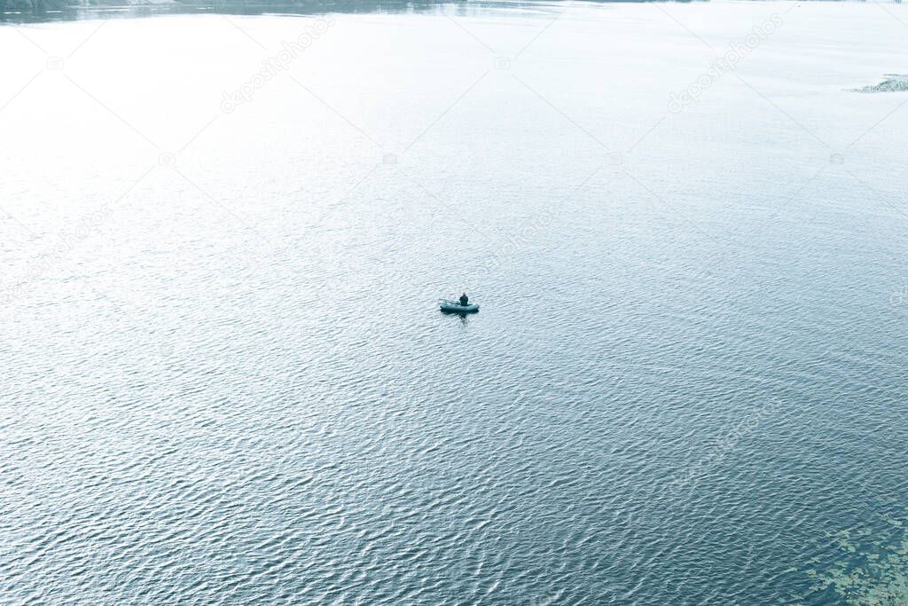 Man in an inflatable boat with a fishing rod in the sea
