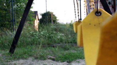 Bahçede çocukların sarı salıncakları zincirli