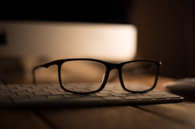 Görüş ve görüş düzeltme için gözlük ve klavyedeki ahşap masadaki bilgisayardan koruma