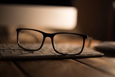 Görüş ve görüş düzeltme için gözlük ve klavyedeki ahşap masadaki bilgisayardan koruma