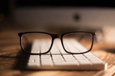 Görüş ve görüş düzeltme için gözlük ve klavyedeki ahşap masadaki bilgisayardan koruma