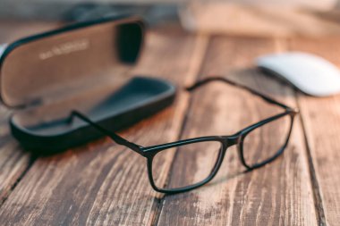 Görüş ve görüş düzeltme için gözlük ve ahşap masada ptotlama çantası olan bilgisayardan koruma.