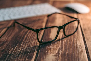 Gözlük, görüş düzeltme ve ahşap masadaki bilgisayardan koruma.
