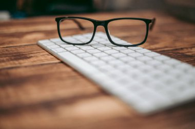 Görüş ve görüş düzeltme için gözlük ve klavyedeki ahşap masadaki bilgisayardan koruma