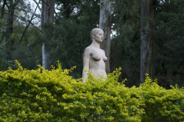 Doğayla dolu güzel bir parkta bir kadın heykeli.