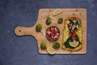 Tahta bir masada ıspanaklı domates ve peynirli omlet.