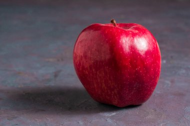 Gri bir masanın üzerinde yalıtılmış bir elma. Lezzetli ve sağlıklı meyve..