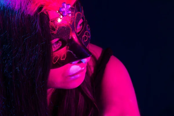 A woman in a red mask in a bar with pink and blue light.Up down view.