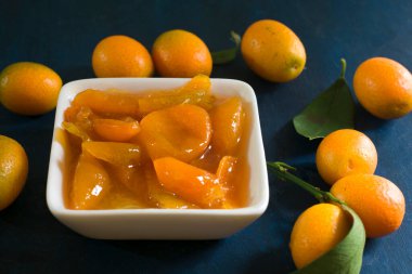 Bir sürü kumkat ve mavi arka planda yapraklar.