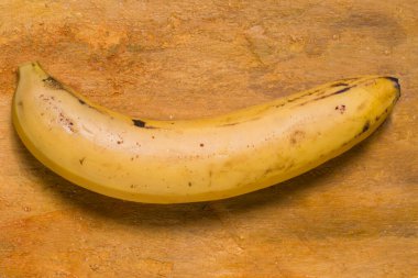 Sarı bir masada yalıtılmış bir muz. sağlıklı meyve ve tam sarı renk.