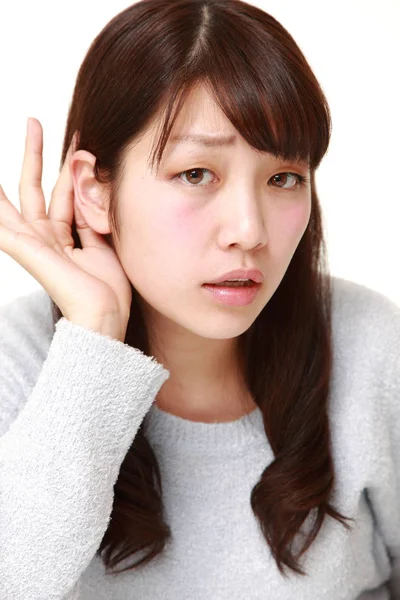 Young woman with hand behind ear listening closely — Stock Photo, Image