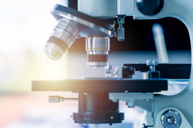 Yakın çekim mikroskop lensleri örnek kaydırağında ve arka planda ışık fişeği var. Seçici odaklanma. Biyoloji bilimi ve tıbbi konsept.